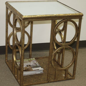 Gold decorative side table with a glass top on a plain background