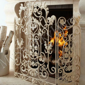 Decorative fireplace screen with intricate designs in front of a lit fireplace.