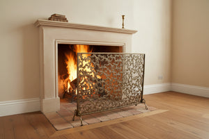 Decorative fireplace screen with intricate gold patterns on a white background