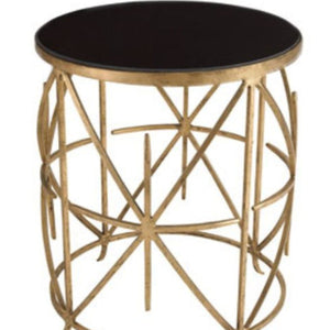 Small round table with black top and gold geometric base on a white background