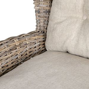 Close-up of a woven wicker or rattan chair arm and seat cushion in a light beige fabric, with part of a matching back cushion visible against a white background.