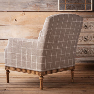 Chair with plaid pattern in a rustic room with wooden walls and floor.