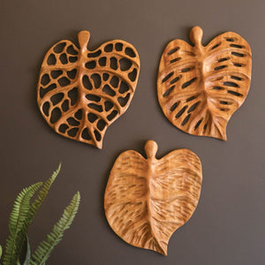 Three carved teakwood leaf wall art pieces
