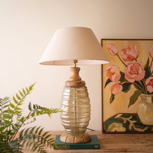 Glass and wood table lamp with fabric shade styled on a table