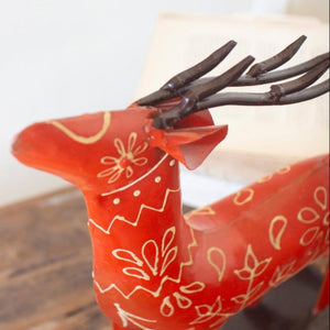 Close-up of raised white folk-art painting on red metal reindeer