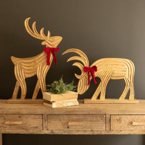 Velvet Ribbon Mango Wood Reindeer, set of 2 carved gold-washed reindeer with red velvet bows on a console