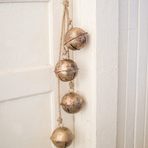 Aged metal hanging bells in distressed gold on a jute rope
