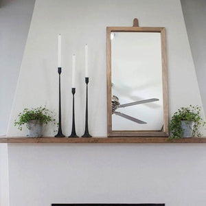 Cast iron taper candlesticks on a wood shelf with a mirror