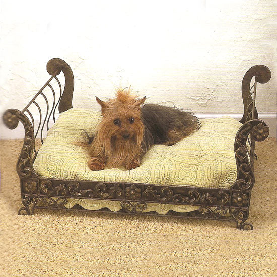 Small dog resting in a decorative wrought iron pet bed