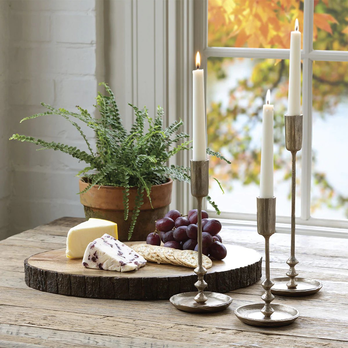 Metal taper candle holders styled beside a window