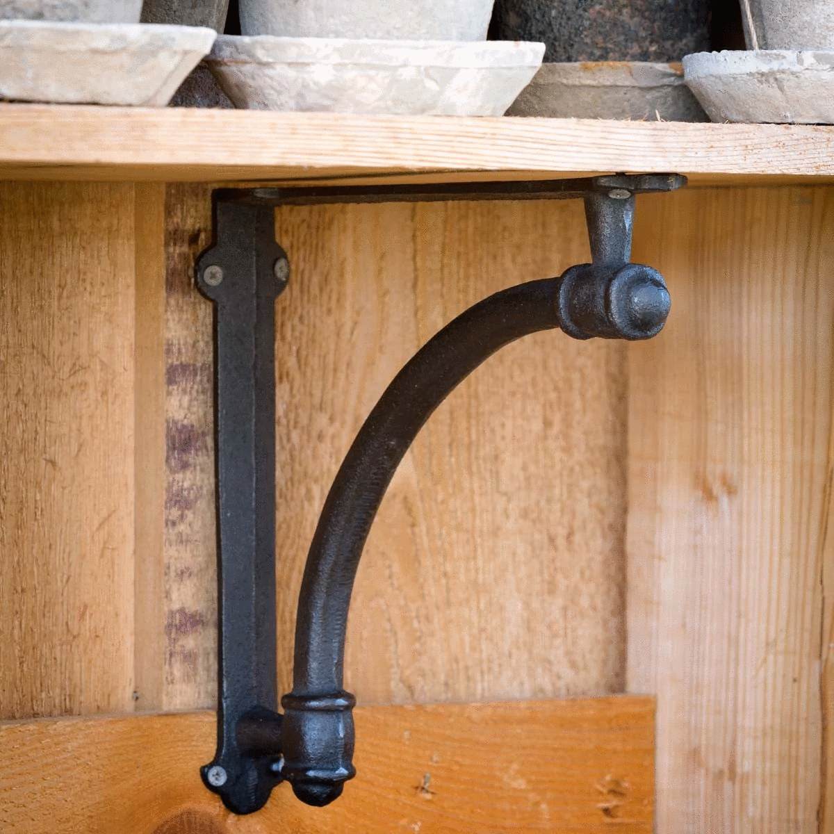Decorative black iron shelf bracket supporting a wood shelf