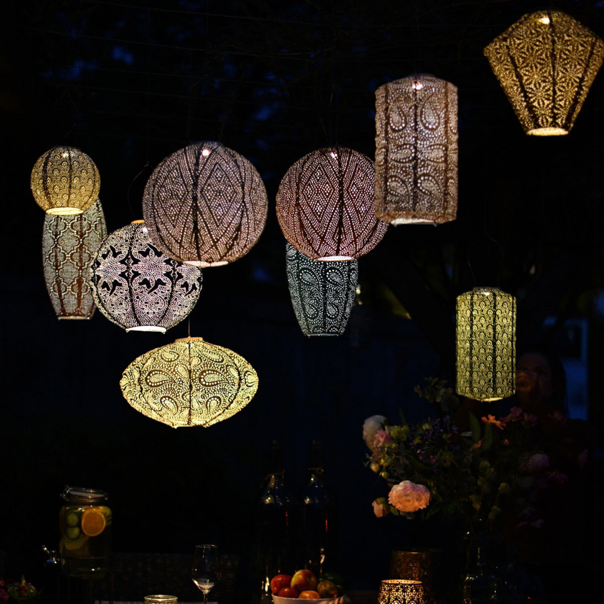 Patterned hanging lanterns glowing outdoors after dark
