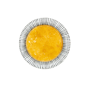 A round glass plate with a bold yellow center and black and white striped rim.