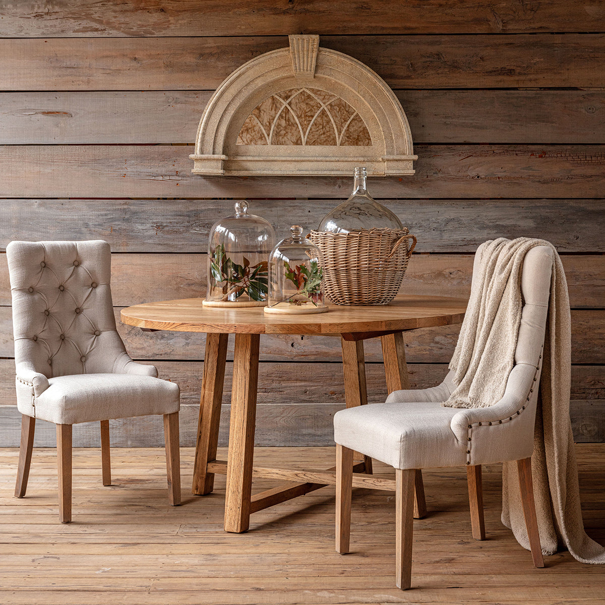 Wooden dining table with two chairs against a wooden wall.