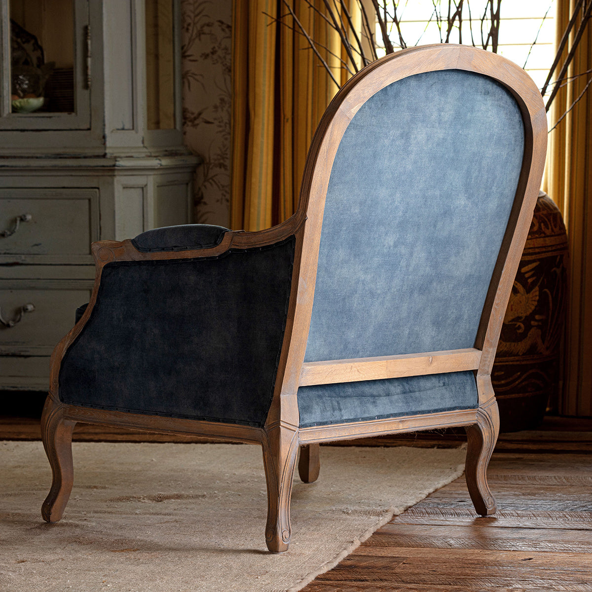 Blue velvet armchair with wooden frame in a room setting
