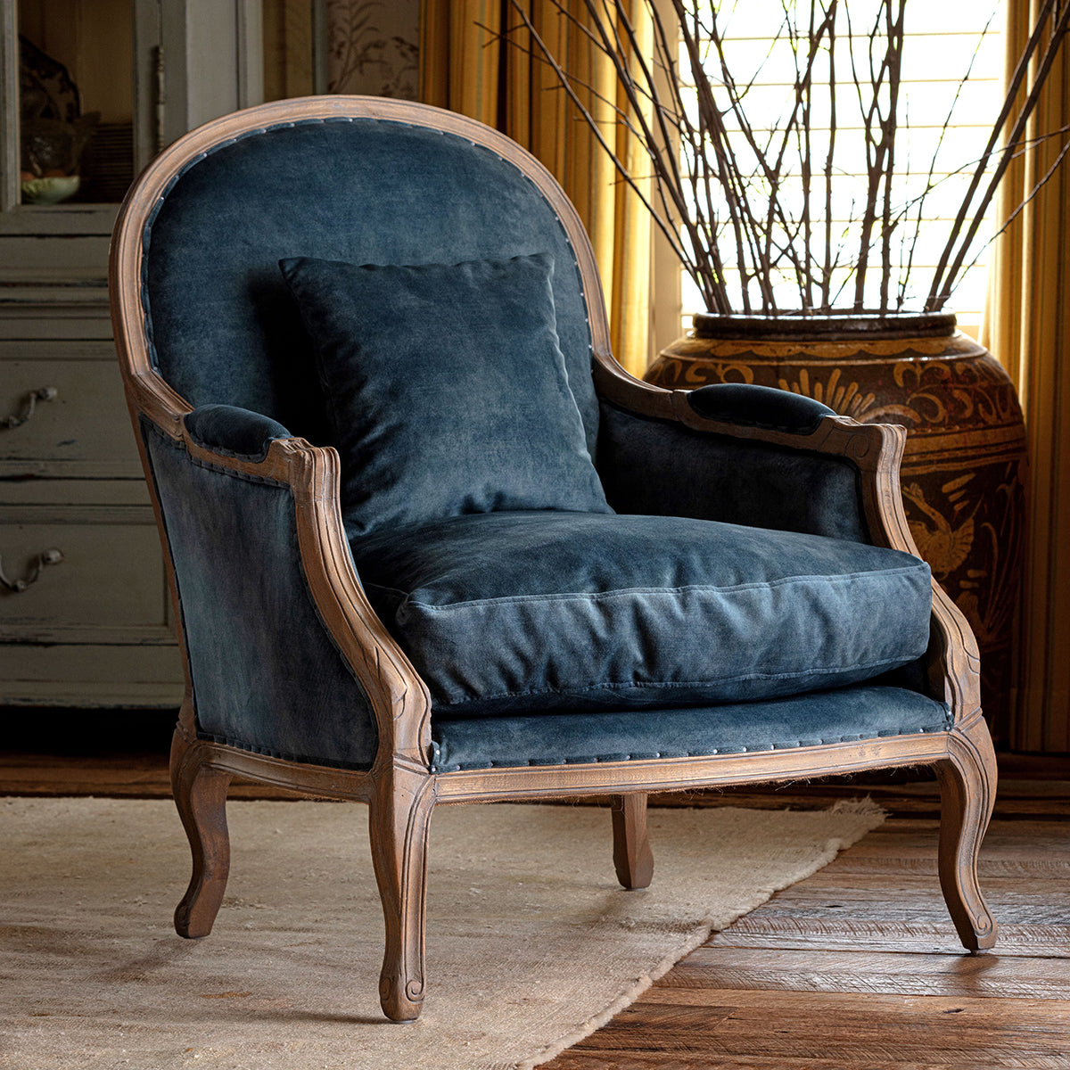 Blue velvet armchair with wooden frame in a room setting