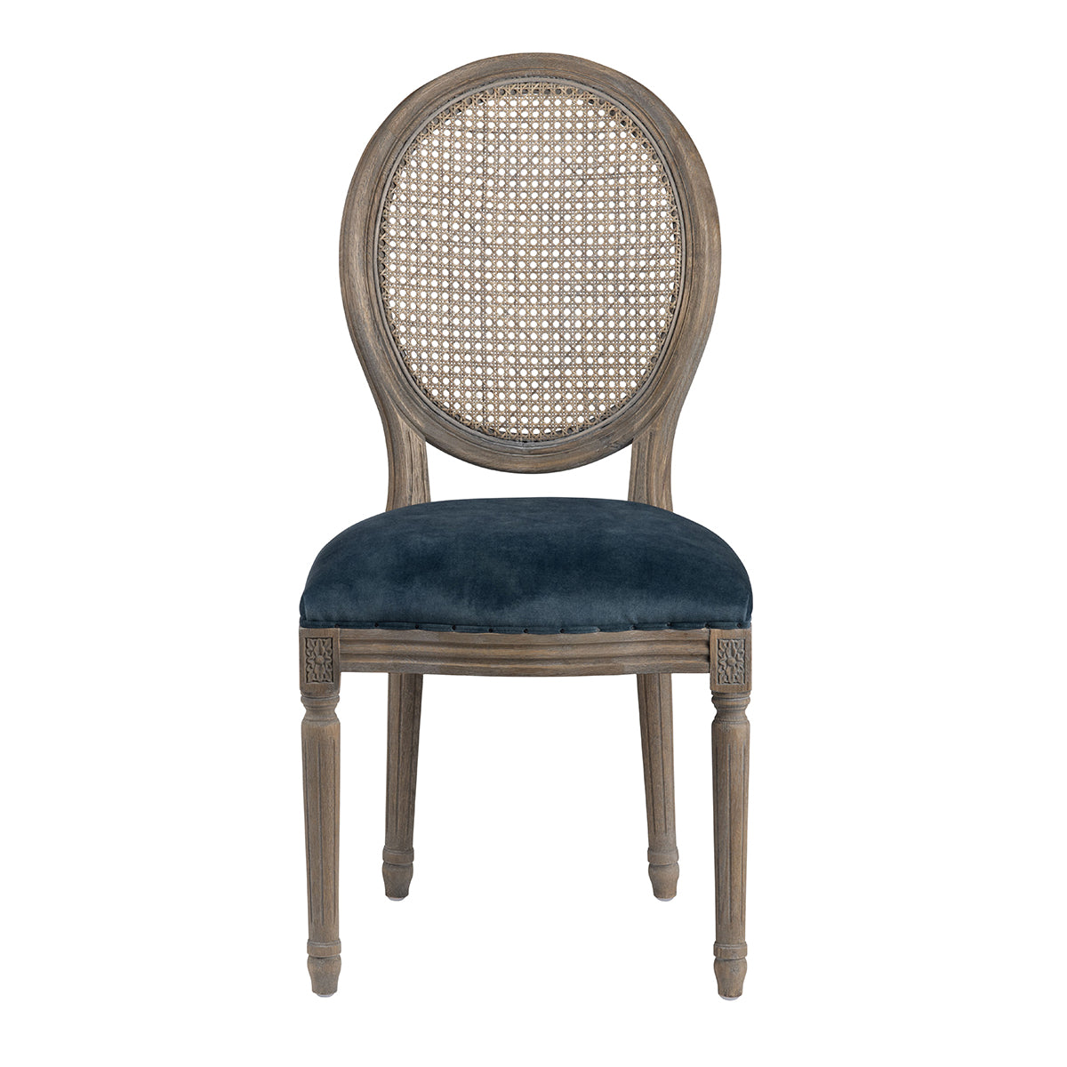 An oval-back dining chair with a distressed gray-brown wood frame, a woven cane backrest, and a deep navy blue velvet upholstered seat, shown against a plain white background.