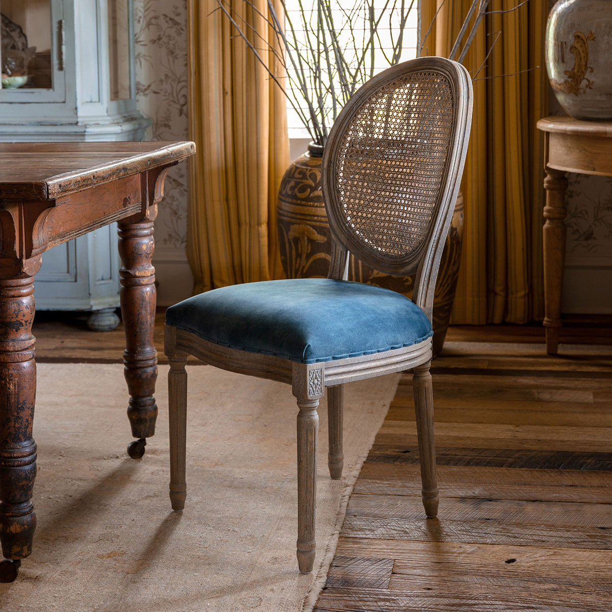 Chair with blue cushion and wicker backrest in a room with wooden floor and furniture.