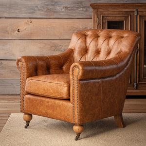 A classic tufted leather armchair in a warm cognac brown, styled in a rustic room setting with a wooden wall, a wooden cabinet, and a woven rug.