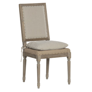 A tall wooden dining chair with a distressed gray-brown frame, beige upholstered backrest and seat cushion, and nailhead trim, shown on a plain white background.