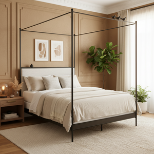 A four-poster canopy bed with a black metal frame and a white upholstered headboard, styled in a warm beige bedroom with neutral bedding, plants, and wood-paneled walls.