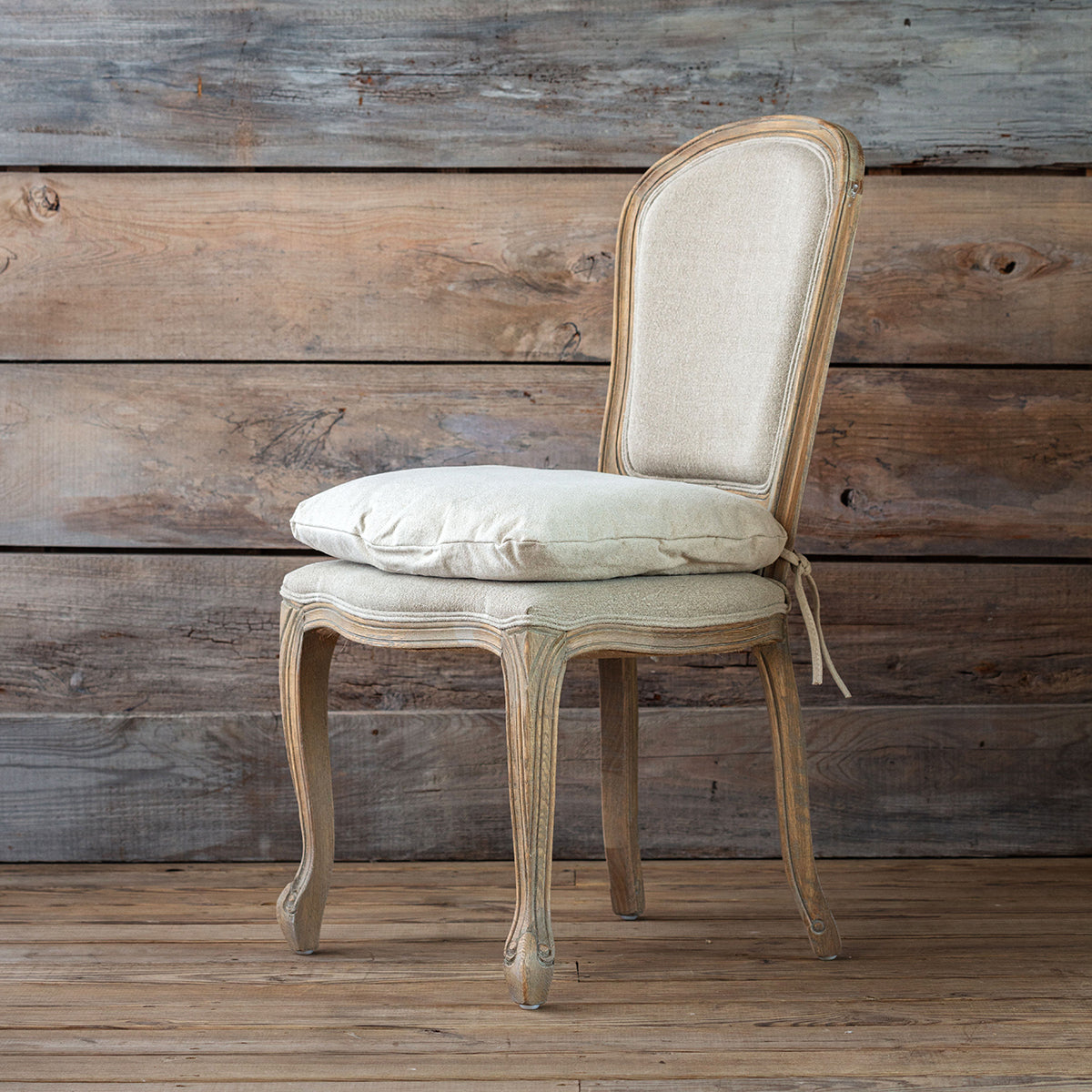 Vintage-style chair with beige cushion against a wooden wall.