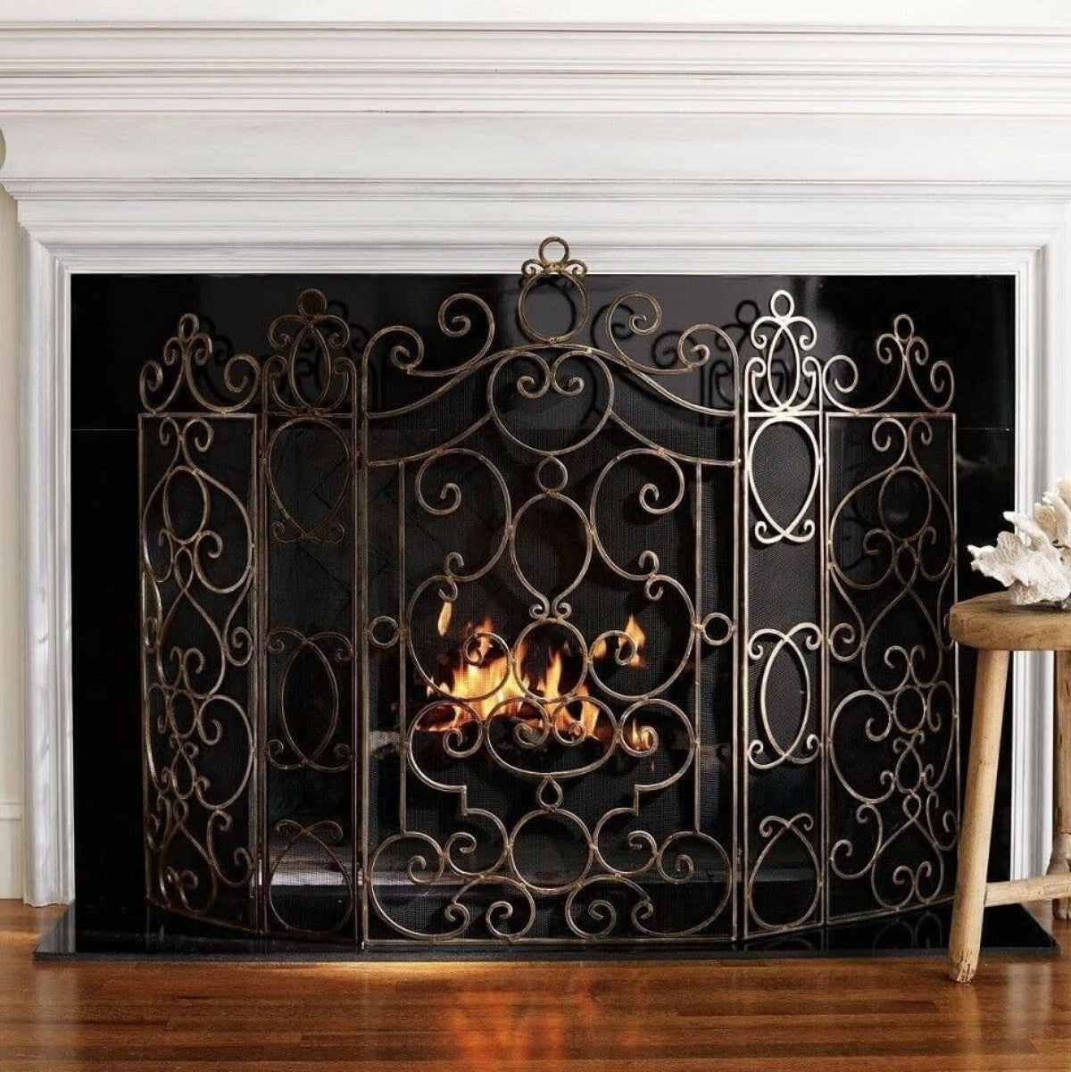 Decorative metal fireplace screen with intricate designs on a white background