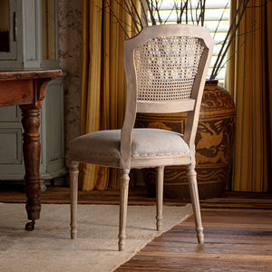 Vintage-style chair with a wooden frame and woven backrest in a warm, decorated room.