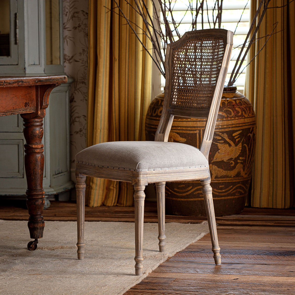 Chair with a woven backrest in a room with wooden furniture and yellow curtains.