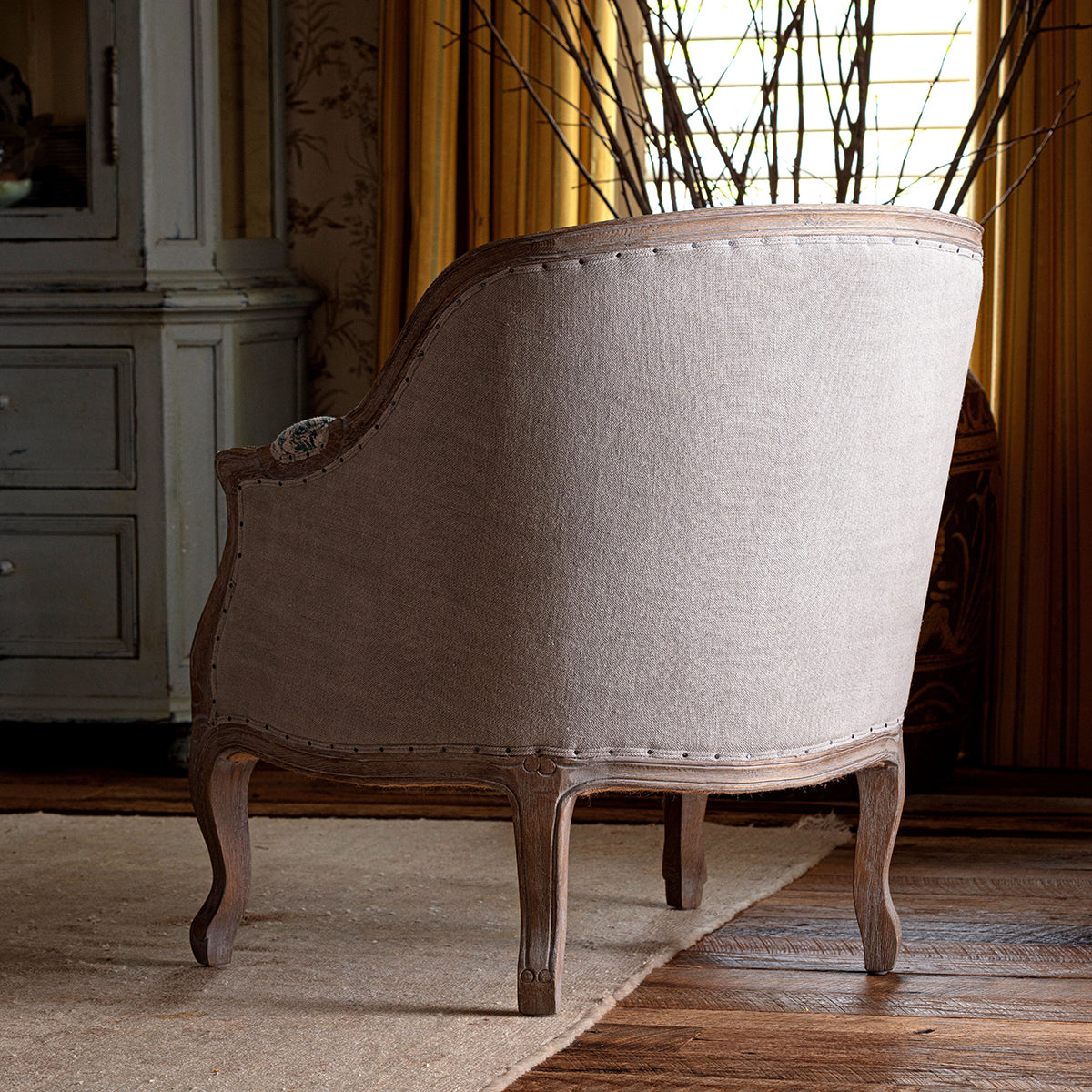 Vintage-style armchair with floral patterned backrest in a room with wooden floor and furniture.