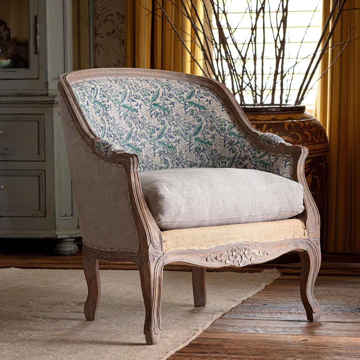 Vintage-style armchair with floral patterned backrest in a room with wooden floor and furniture.