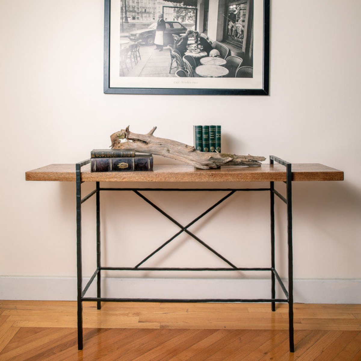 Hand-forged iron console table with a thick wood top styled beneath framed artwork