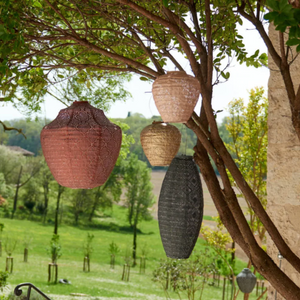 Decorative hanging lanterns in a garden setting with trees and greenery.