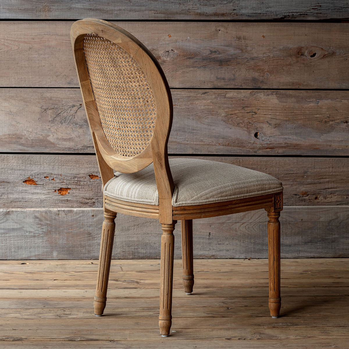 Wooden chair with wicker backrest against a wooden wall. Rosemere Round Cane-Back Dining Chair