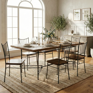 A rectangular wooden dining table with a rustic finish and black metal legs, surrounded by six matching black metal chairs with wooden seats, set on a woven jute rug in a bright, modern dining room.
