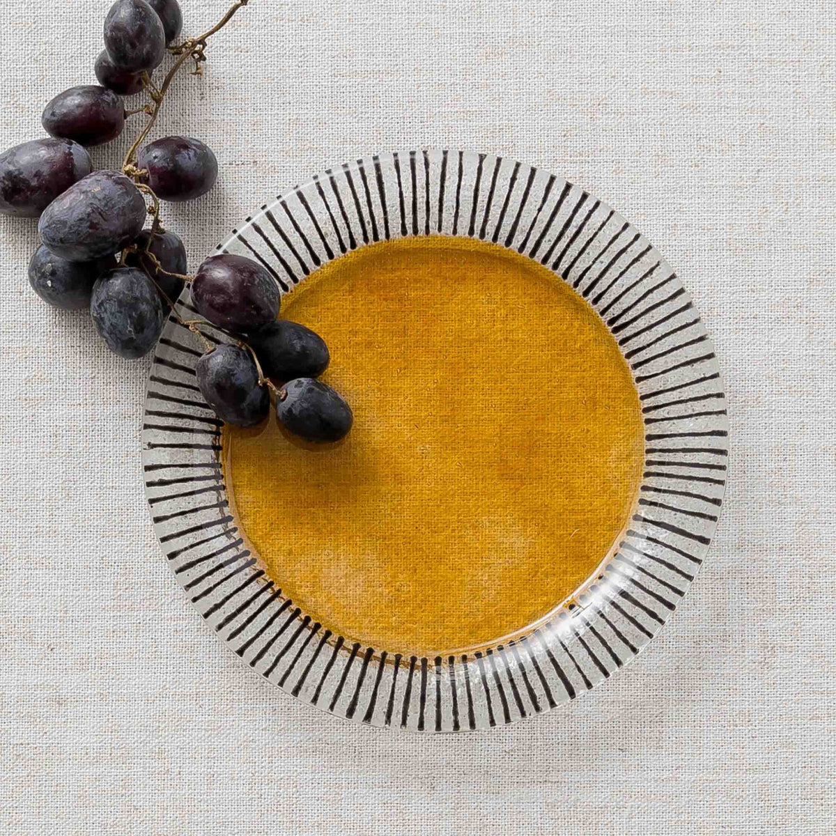 A round glass plate with a bold yellow center and black and white striped rim.