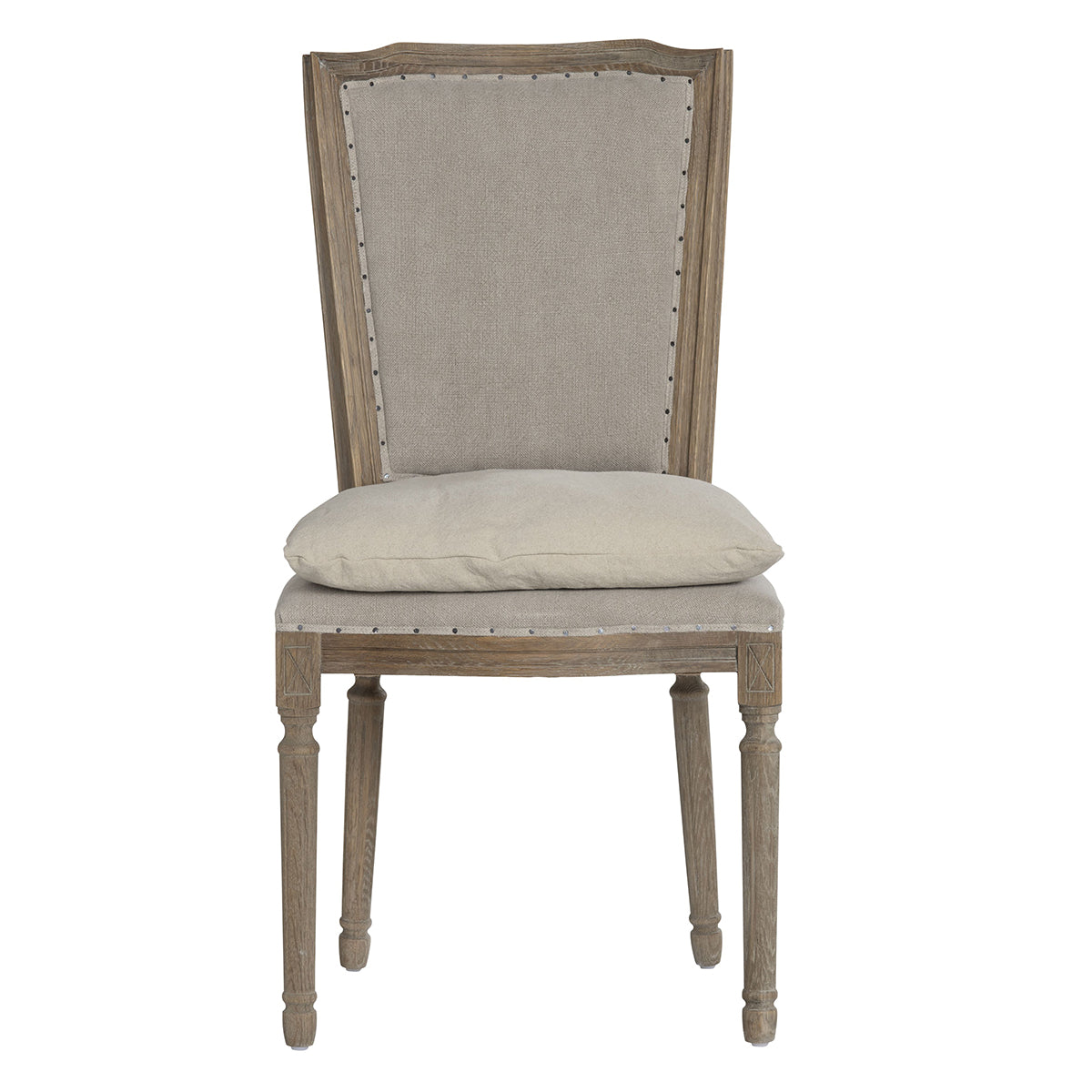 A classic high-back dining chair with a distressed gray-brown wood frame, featuring light beige fabric upholstery on the backrest and seat cushion, accented with silver nailhead trim.