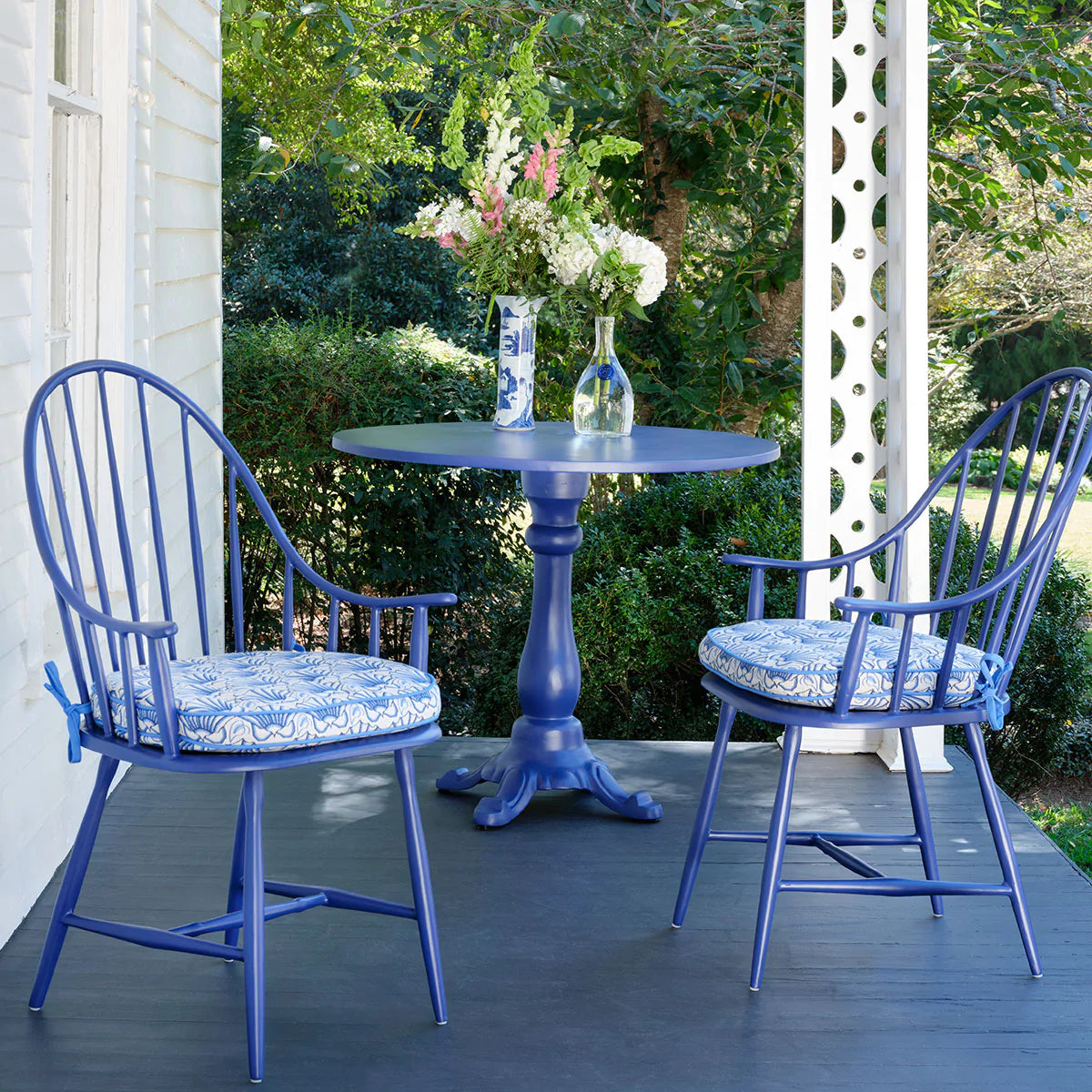 Cast aluminum patio chairs and table arranged on a covered porch