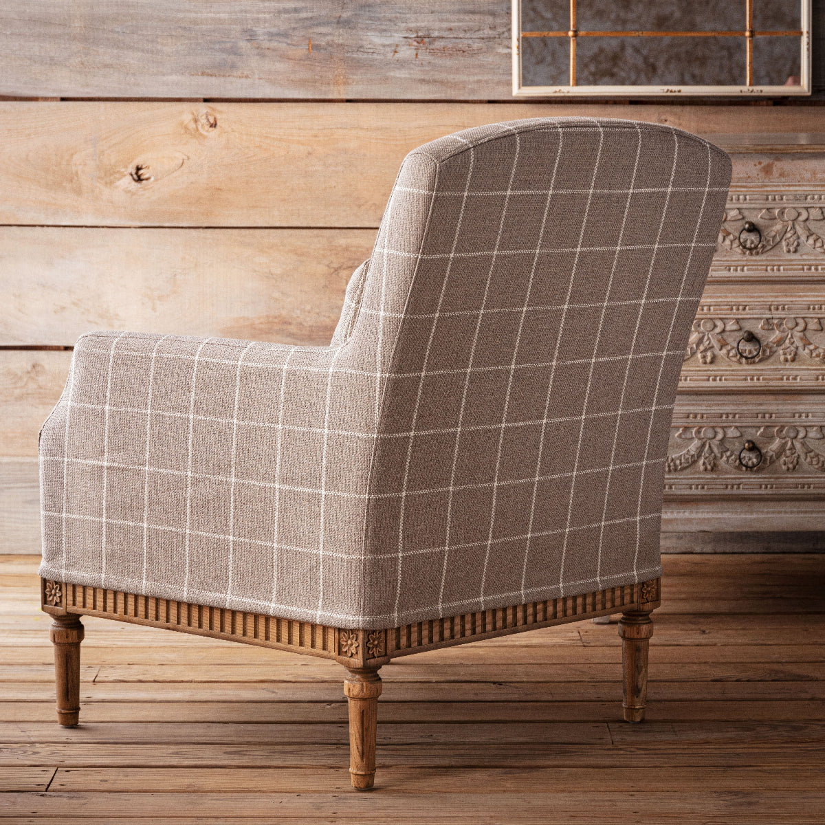 Plaid armchair with wooden legs in a rustic room setting