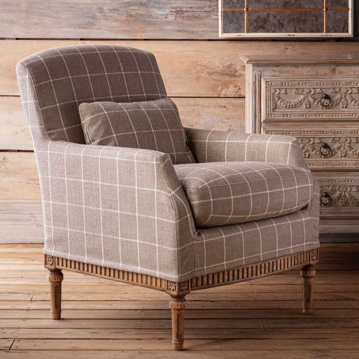 Plaid armchair with wooden legs in a rustic room setting