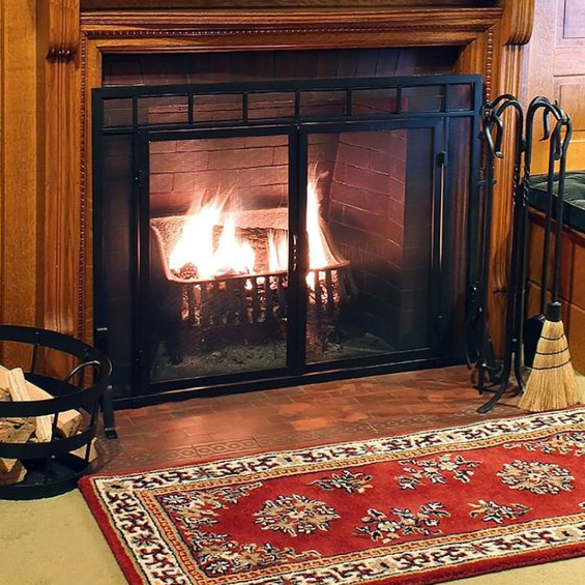 Fireplace with a lit fire, surrounded by wooden paneling and a decorative rug.