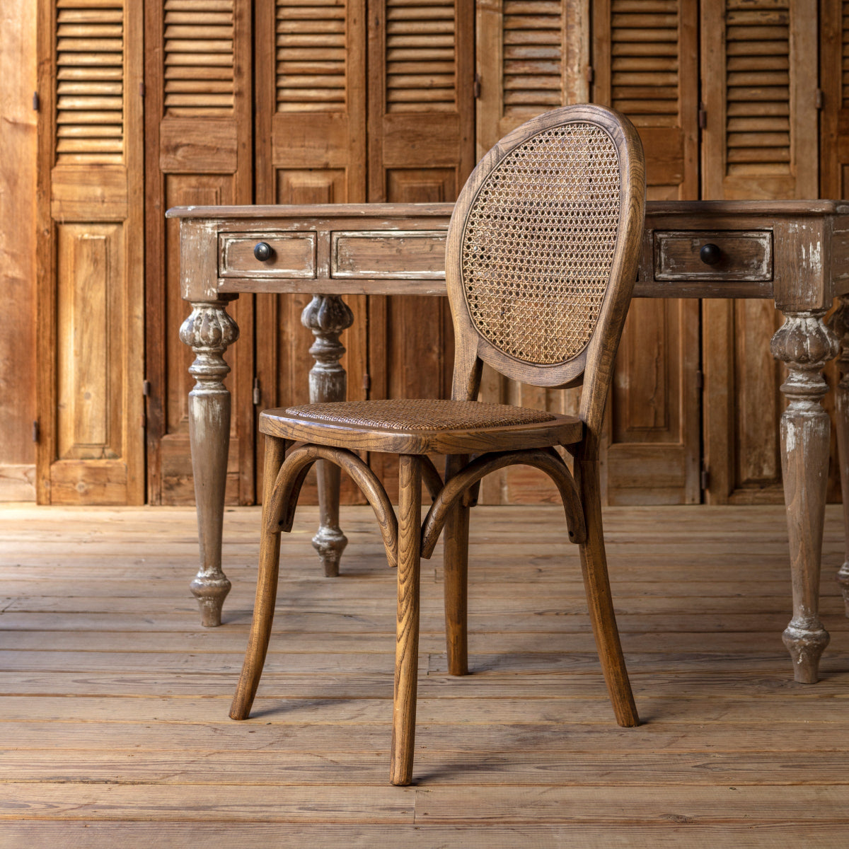 Bellhaven Cane Back Dining Chair beside a rustic wood desk, showing its oval cane back and bentwood frame
