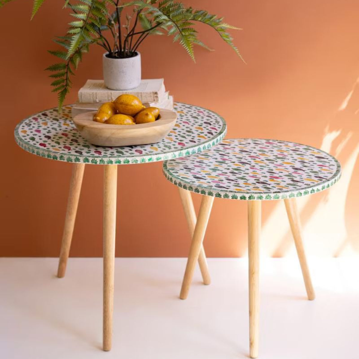 Set of two round fish mosaic accent tables styled in a room