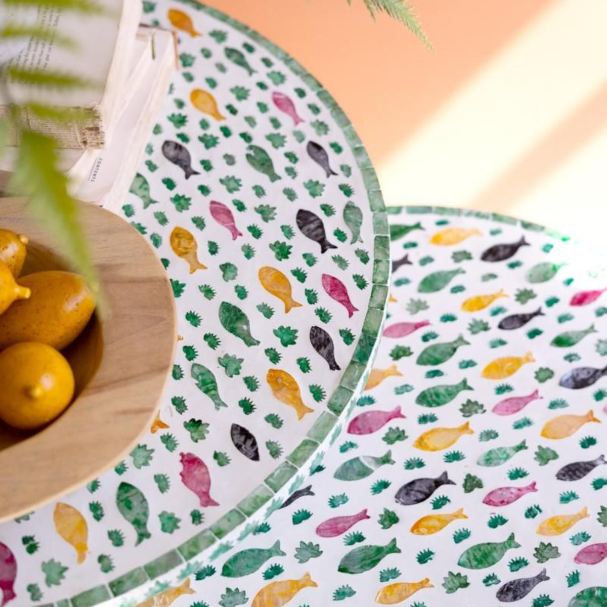 Capiz Fish Mosaic Nesting Tables styled with a plant against a terracotta wall
