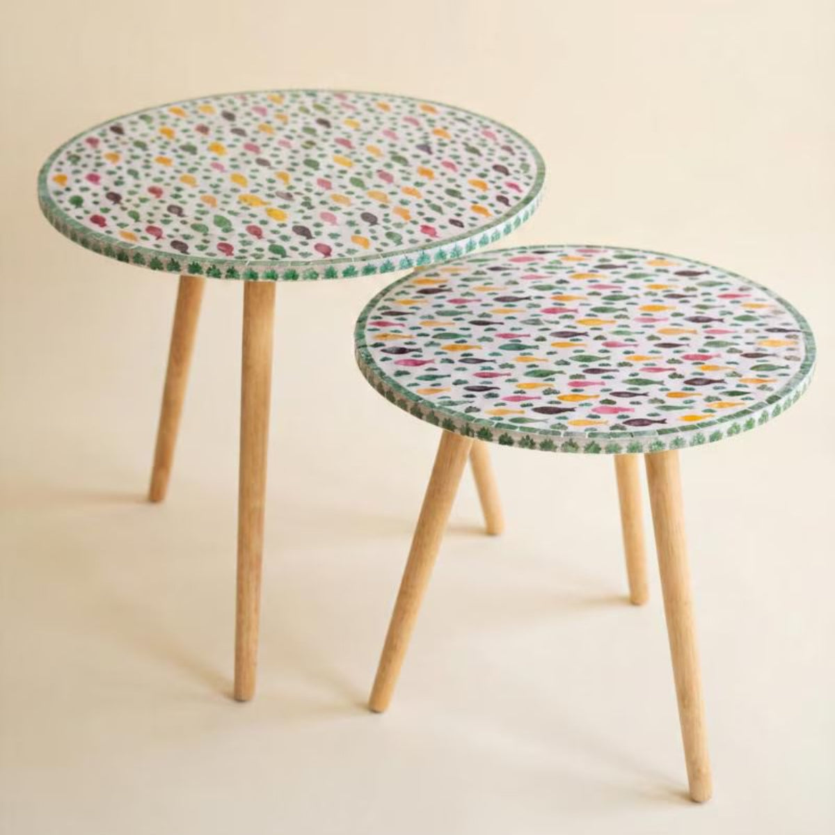 Two capiz fish mosaic accent tables with tapered wood legs on a white background