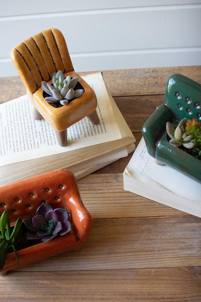 Ceramic chair and sofa planters with succulents on a wood table