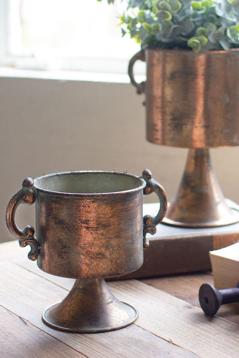 Two antique copper footed urn planters with greenery