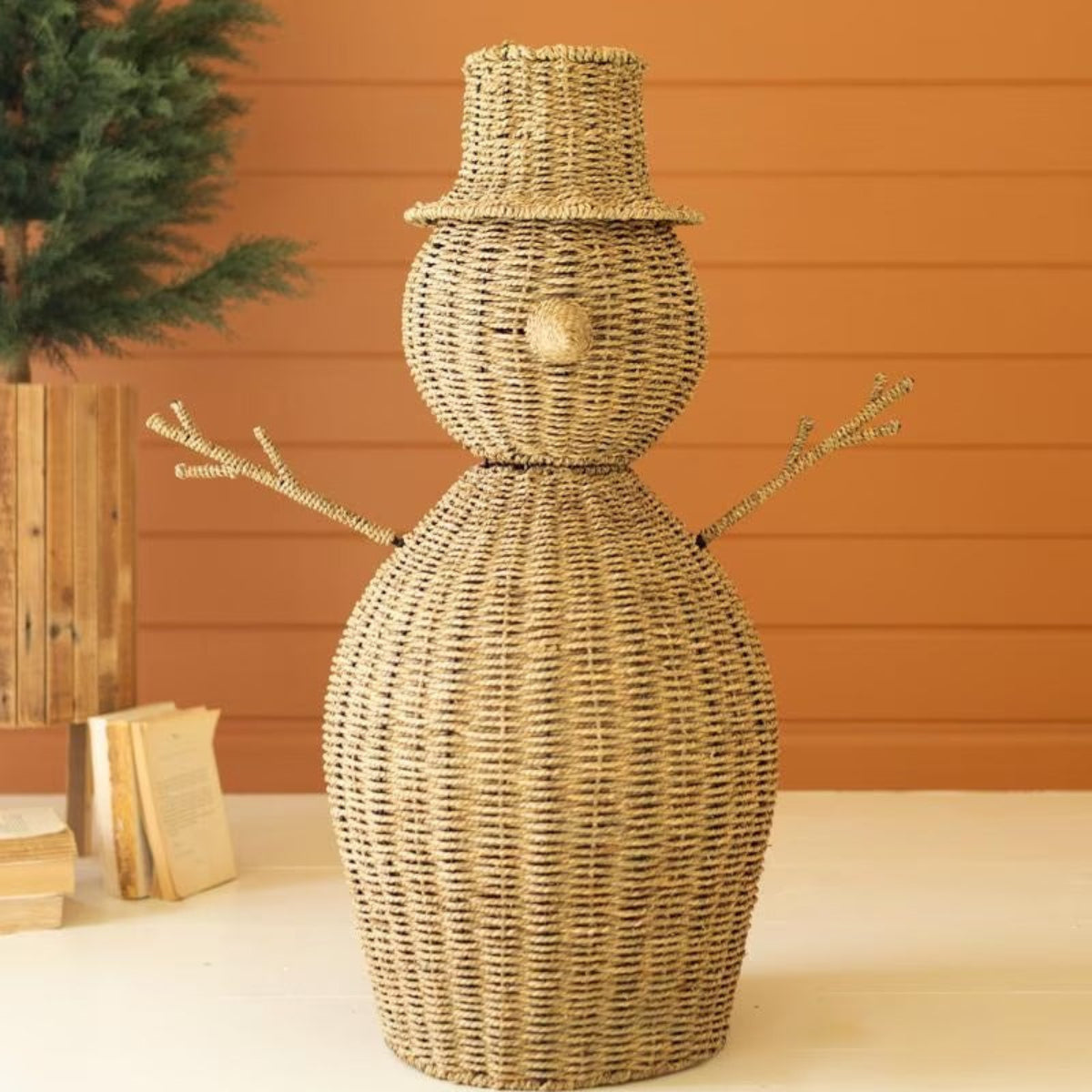 Woven seagrass snowman displayed beside a Christmas tree