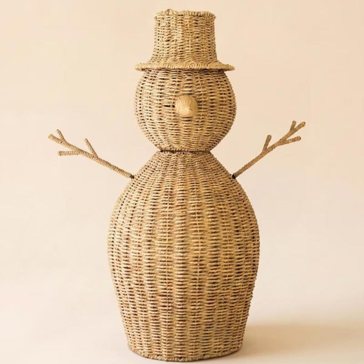 Woven seagrass snowman displayed beside a Christmas tree