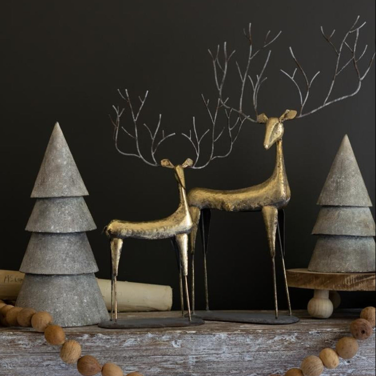 Gold metal reindeer pair styled with white trees and wood bead garland